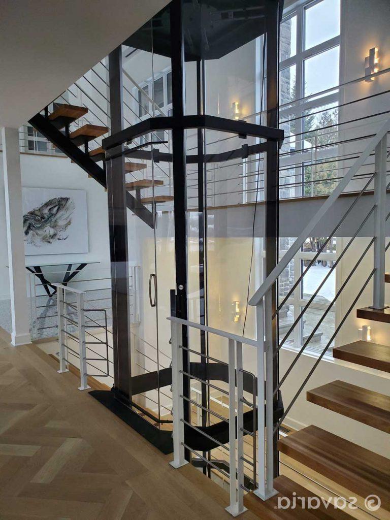 Octagonal glass elevator with black trim in luxury home